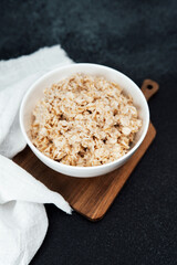 Creamy oatmeal served in a white bowl on a wooden cutting board