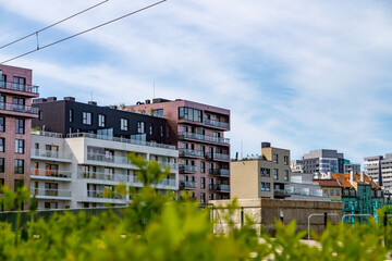 fragment of a modern housing estate in Wrocław. You can see several multi-family buildings with modern architecture, with facades in white, beige and brick pink. Some of the apartments have balconies  © Adam