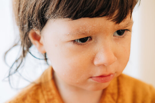 Close-up of a serious toddler with water droplets on her face