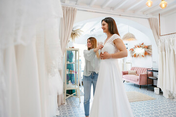 Wedding planner assisting bride choosing perfect dress 