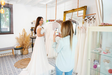 Wedding planner taking pictures of bride wearing dress