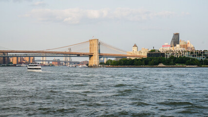 A bridge spans a river in a city with a skyline in the background