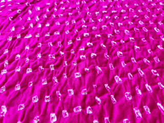 Tiny white Bandhani dots punctuate the pink silk fabric, creating a subtle, textured surface.