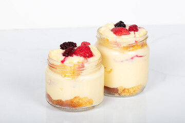 Delicious creamy dessert in glass jars topped with fresh strawberries, blackberries, and raspberries, perfect for sweet moments, homemade treats, and dessert lovers