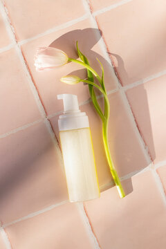 Face cleaning foam product bottle with tulip, mockup on a tile surface