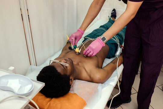 A cardiologist prepares the cardiograph sensors for an ECG procedure.