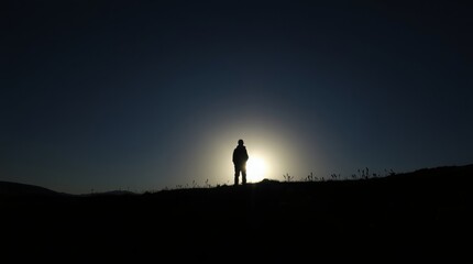 Solitary Silhouette: A solitary figure, dwarfed by the vastness of the setting sun, stands silhouetted against the horizon, embodying themes of solitude, introspection, and the pursuit of inner peace.