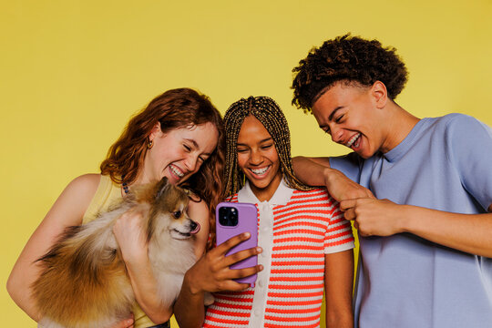 Three happy friends watching funny videos on smartphone