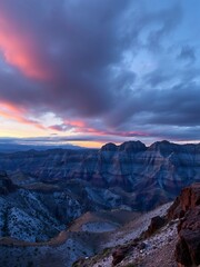 an image of a person standing on a cliff overlooking a valley, there is a man standing on a cliff overlooking a valley