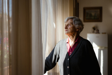 A woman at home is looking out of the window