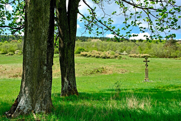 Wayside old stone cross in Nieznajowa village, Low Beskids, Poland. 
This region are a mountain range with wide open spaces, wildlife, deserted villages and stone crosses by the roadside