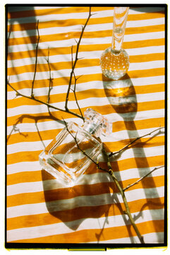Glass perfume bottles on striped fabric with natural shadows