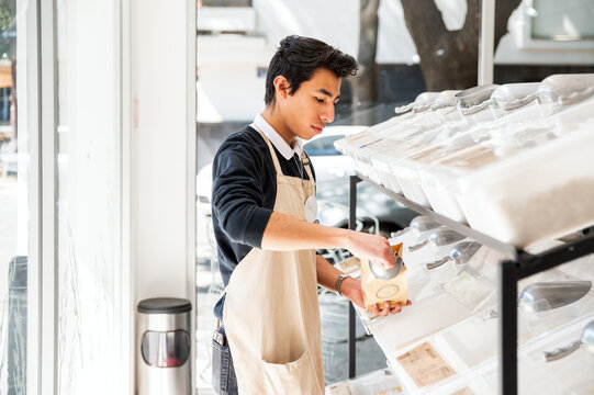 Man filling paper bag at bulk food store in natural light
