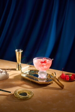 An elegant pink cocktail with cherries and gold barware 