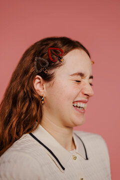 Woman wearing heart shaped hair clips laughing on pink backdrop