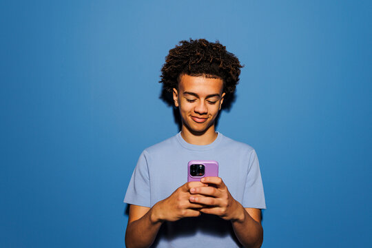 Man using smartphone on blue backdrop