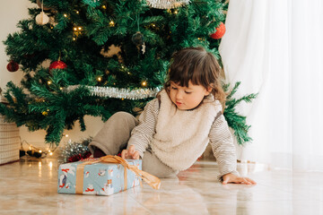 Child with Christmas gift under tree
