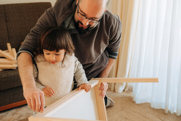 Father teaching his daughter to assemble wooden table together a