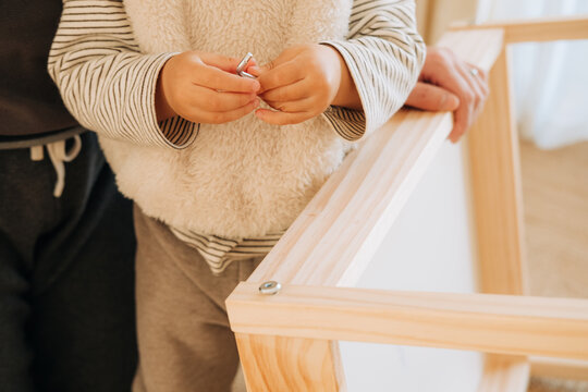 Child holding an Allen wrench while assembling furniture