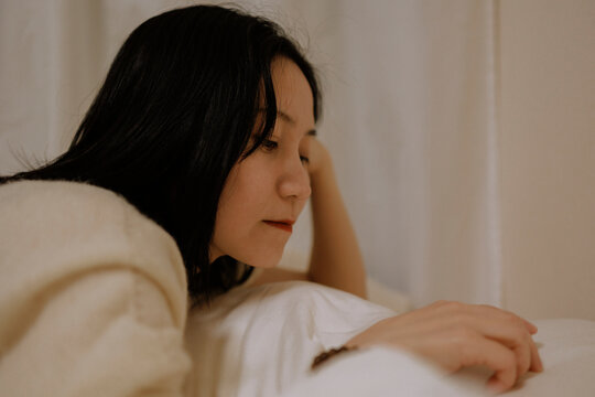 A quiet moment of a young woman contemplating while lying on the bed.