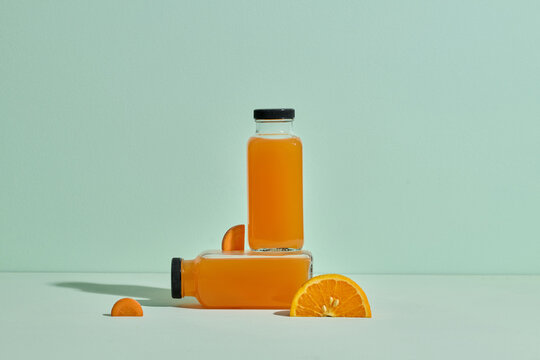 Two clear glass bottles filled with vibrant orange juice  - Powered by Adobe