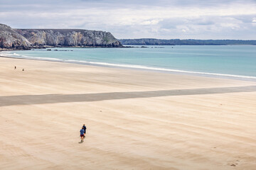 Obraz premium Women walking on a sandy beach heading towards the sea on a sunny summer day