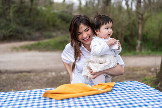 Mother holding her baby girl during picnic in a park