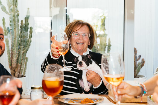Happy senior woman raising wine glass with boston terrier puppy 