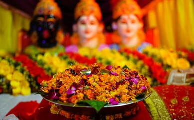A vibrant floral arrangement beautifully displayed on a metallic platter, complemented by a colorful blurred background,