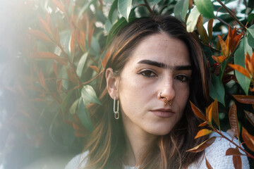 Portrait of a Woman Surrounded by Green and Red Foliage Outdoors