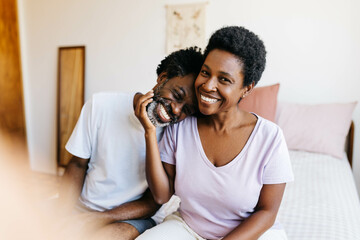 Fototapeta premium Mature black couple cuddling on bed, laughing and relaxing at home