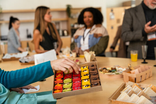 Colorful pastries at a networking event table with people chatti