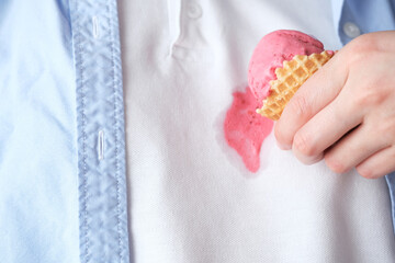 Close-up of pink ice cream in a cone falling onto white clothes during a sweet moment. Concept of...