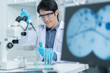 Asian Researcher using a microscope in the clinical lab.male Researcher working in the clinical...