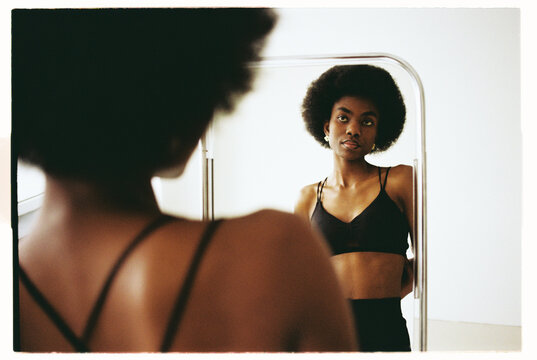 Model poses in front of a mirror showcasing Afro hairstyle 