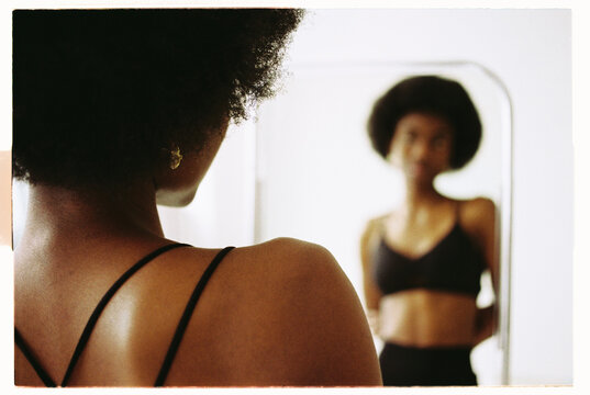 Woman with natural hair observes her reflection in a mirror 