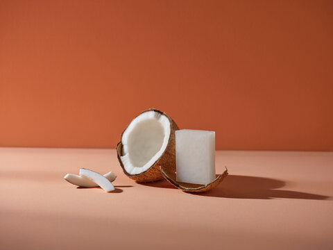 White Soap Bar and Whole and Sliced Coconut on Brown Background