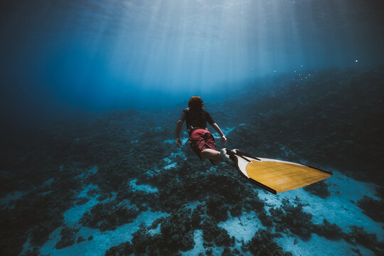 Teenager freediving with golden mono fin
