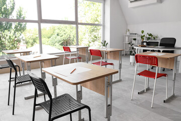 School desks with chairs in modern classroom prepared for exam