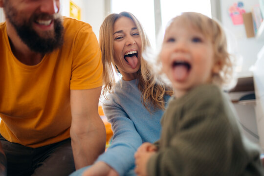 Happy family is sticking out tongues and having fun at home