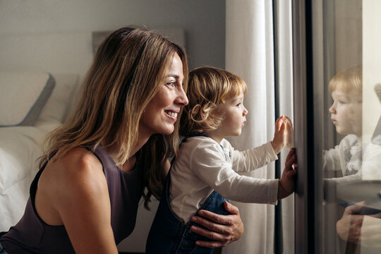 Mother and daughter sharing a tender moment, looking out the window.
