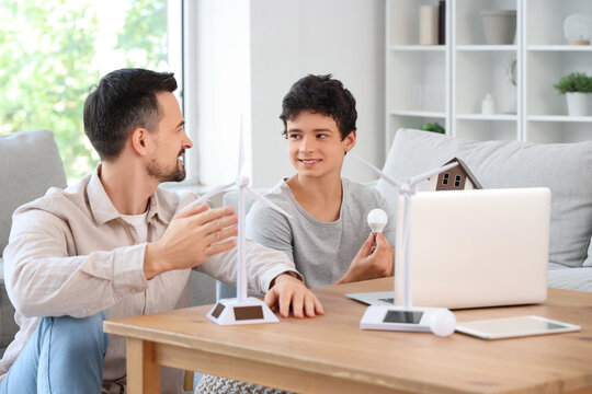 Teenage boy with light bulb and his father talking about wind turbine models at home