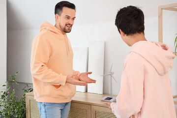 Obraz premium Teenage boy and his father talking about wind turbine models at home