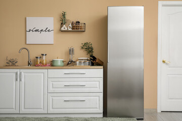 Interior of kitchen with silver fridge, counters and shelf