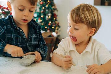 Siblings enjoying hands-on carving activity in festive setting a