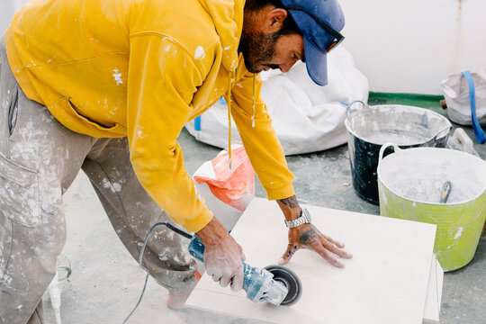 Skilled man using a hand-held cutter to split tiles