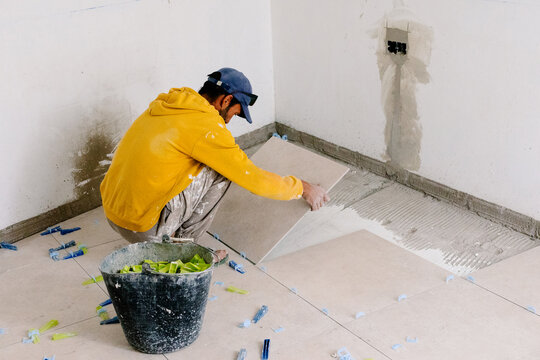 Construction worker installing new floor tiles