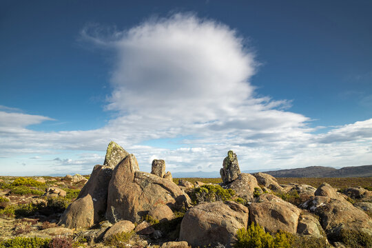 Cloud formations over rock formation on mountain top.