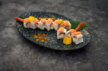 A plate of sushi with a green leaf on top. The sushi is cut into pieces and has a sauce on it