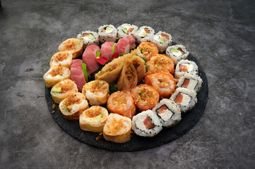 A plate of assorted sushi rolls. Some of the rolls are made with avocado. There are also some rolls with shrimp